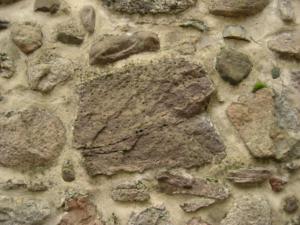 Abb. 1: Jotnischer Sandstein (1. Beispiel) in der Stadtmauer. Man erkennt gut die herausgewitterten Entfärbungsflecken, die dem Stein eine narbige Oberfläche verleihen. Rechts unterhalb des großen Steines befinden sich zwei kleinere Jotnische Sandsteine.