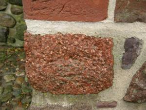 Abb. 32: Ein Åland-Quarzporphyr in der Stadtmauer. Bei diesem nach einer Reparatur frisch eingefügten Geschiebe sind die Gesteinsfarben noch besonders kräftig.