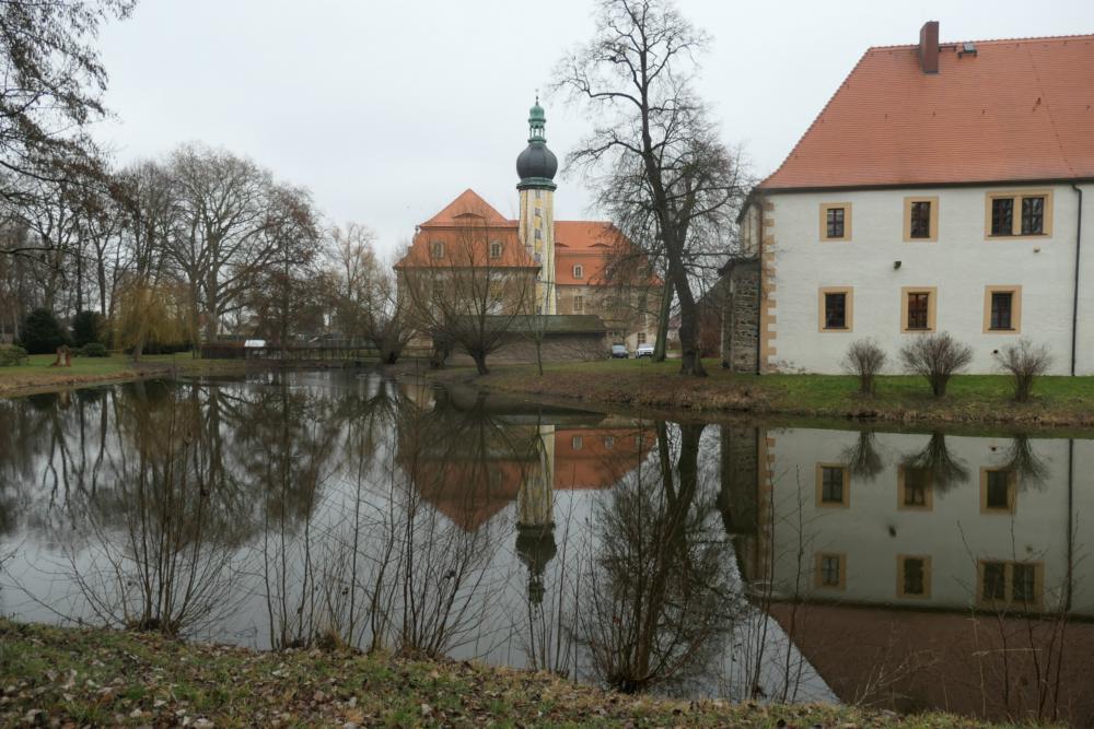 Abb. 1: Hof: Das alte Renaissanceschloss (rechts), gestalterisch vereint mit dem in der Bildmitte aufragenden Barockschloss, spiegelt sich im teichartig erweiterten Burggraben der ehemaligen Wasserburg.